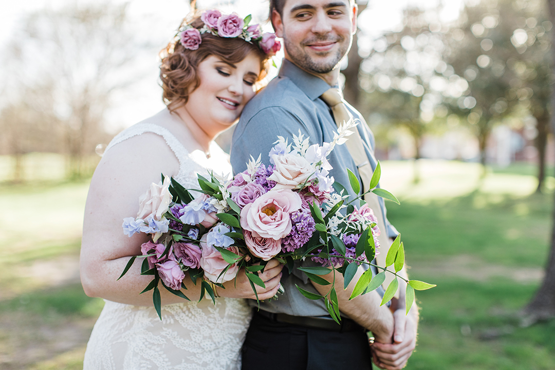 bride in flower crown and groom looking back at each other and holding bouquet